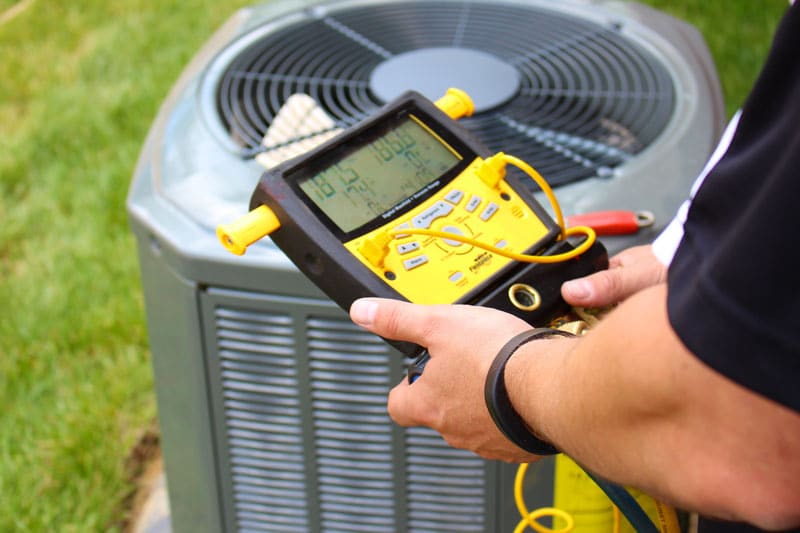 A City View Plumbing, Heating & Air Conditioning HVAC certified technician examines an outdoor air conditioner
