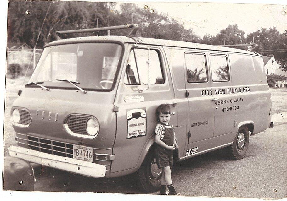 A black and white image of a young child leaning against a City View Plumbing, Heating & Air Conditioning Van